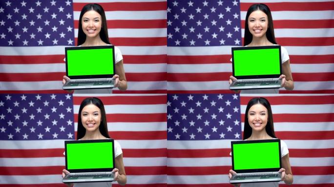 女人拿着带绿屏的笔记本电脑，背景上的美国国旗，语言课程
