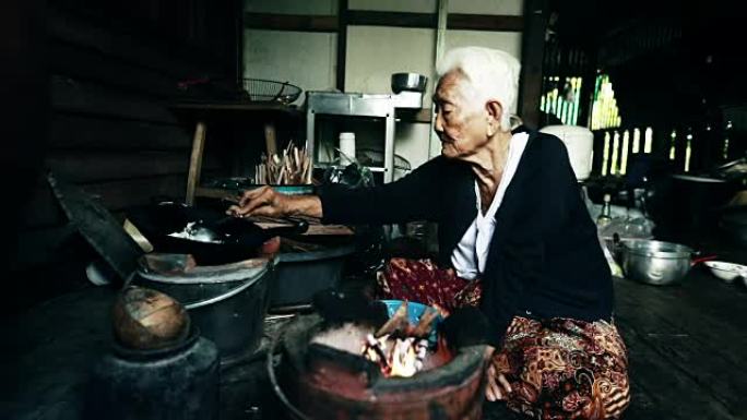 生活方式资深亚洲女性坐在烹饪食物，慢动作