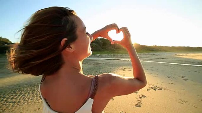 海滩上的高加索女性制作心形手指框