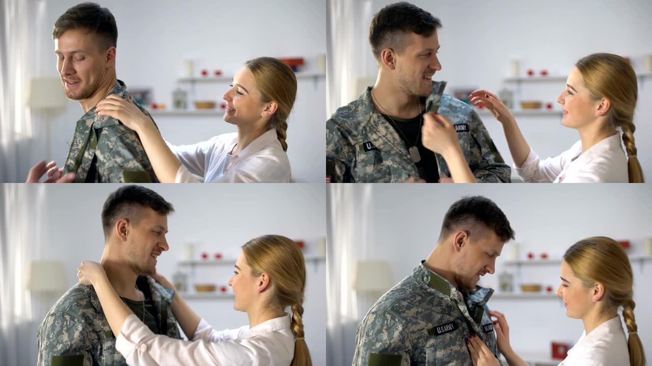 有爱心的妻子帮助穿制服美国男兵微笑着看着情人