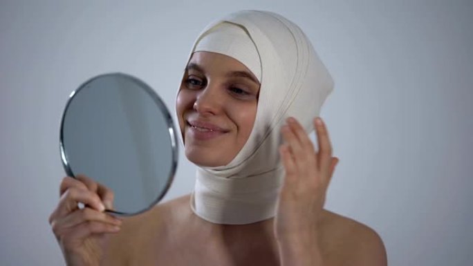 戴头巾的女人看着镜子反射，对整形手术感到满意