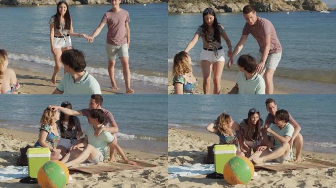 年轻夫妇手拉手在西班牙海滩上与朋友同行