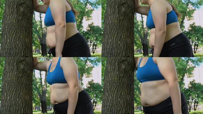 肥胖女士呼吸沉重，站在树下，做运动减肥