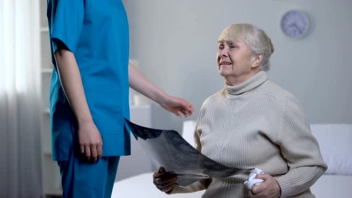 护士支持哭泣的老妇人看着大脑伦琴，致命的诊断