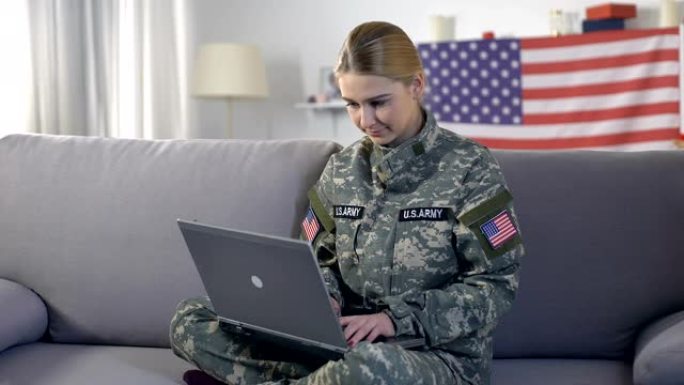 善良的美国女兵一边在笔记本电脑上打字一边看着摄像机，志愿者
