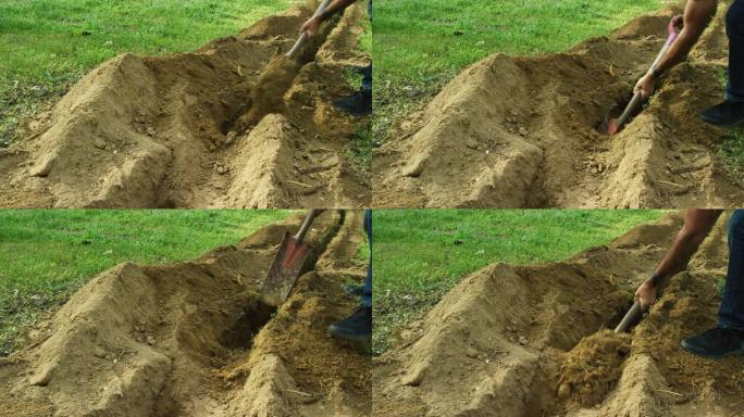 一名白人男子使用挖沟铲手动清除户外草地上的沟渠中的污垢
