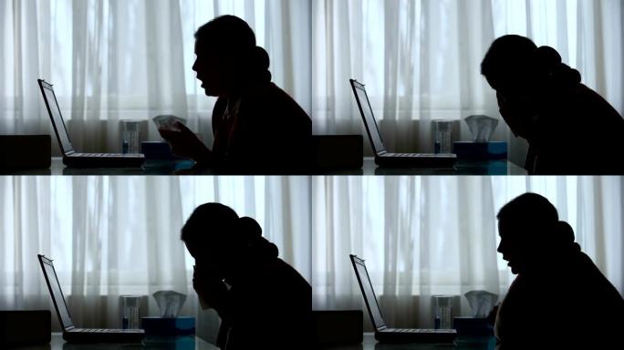 流鼻涕和寒冷的女人的剪影试图在家里的笔记本电脑上工作