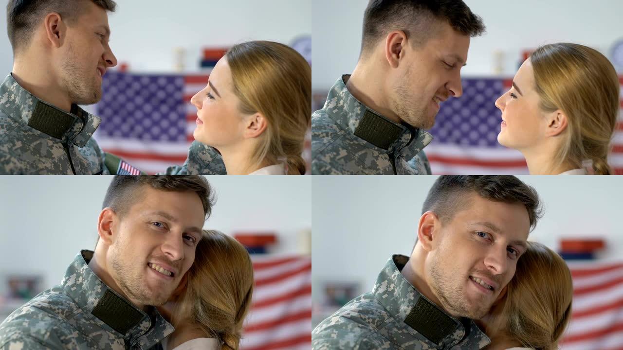 深情的美国士兵拥抱着年轻的妻子，看着镜头，退伍军人返乡