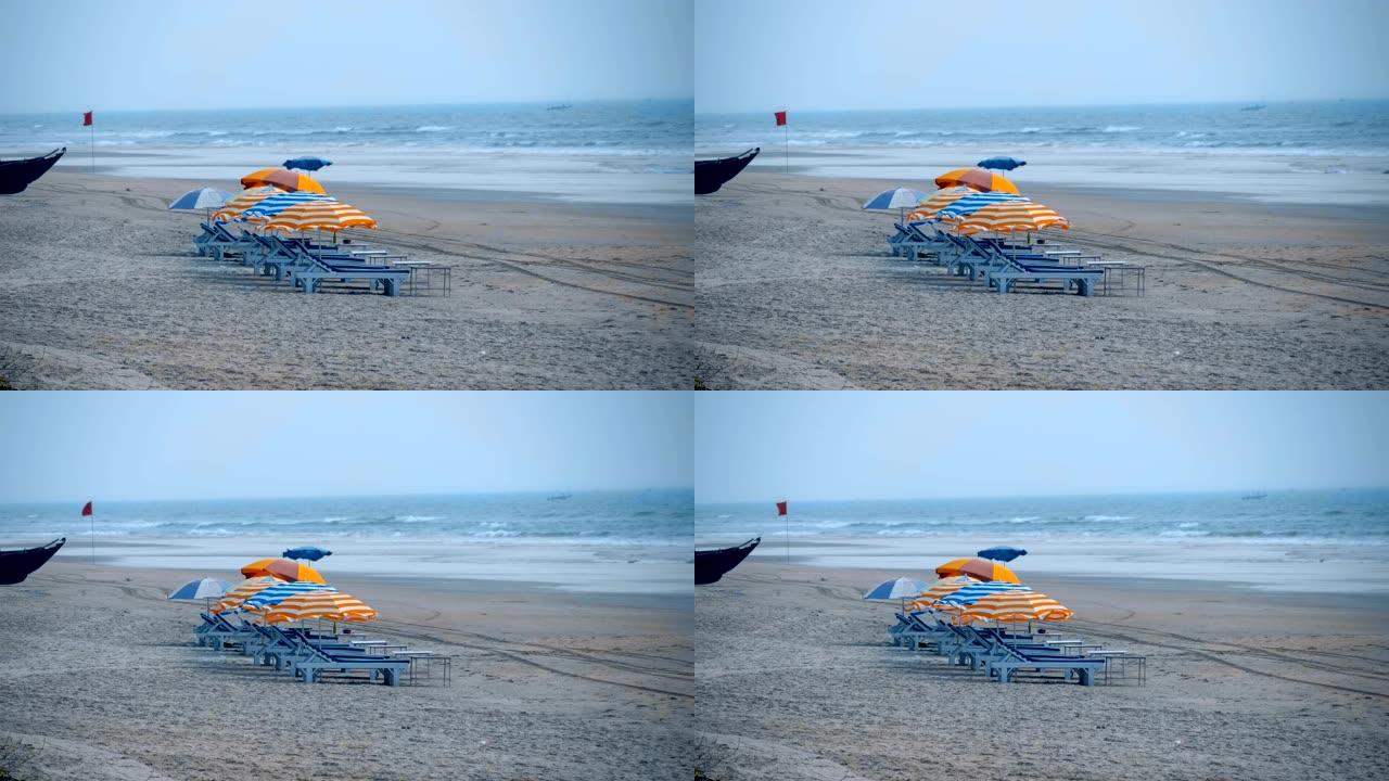 暴风雨的海岸上有日光浴浴床的沙滩伞，警告红旗
