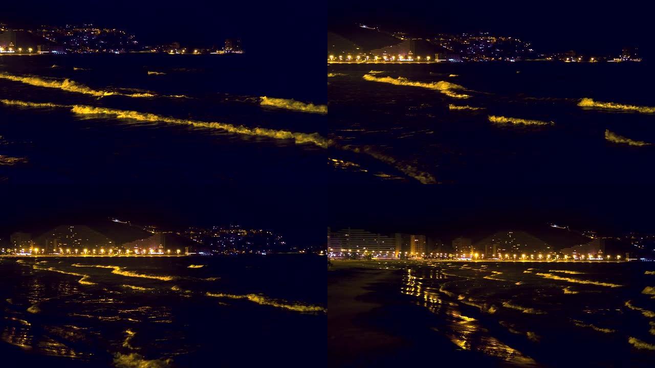 晚上，带有明亮白色波峰的海浪在西班牙度假城市上岸