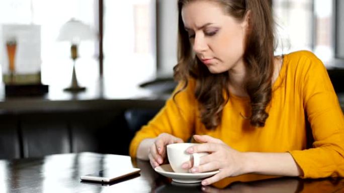 沮丧的女人坐在咖啡馆里，检查智能手机，等待心爱的人打来的电话