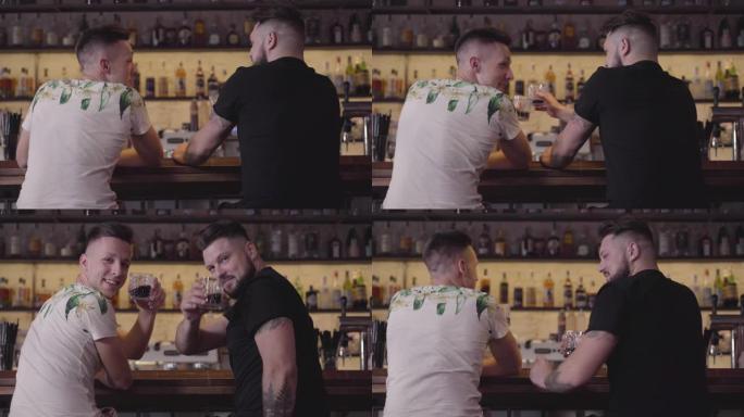 两名男子坐在酒吧柜台喝精英酒。