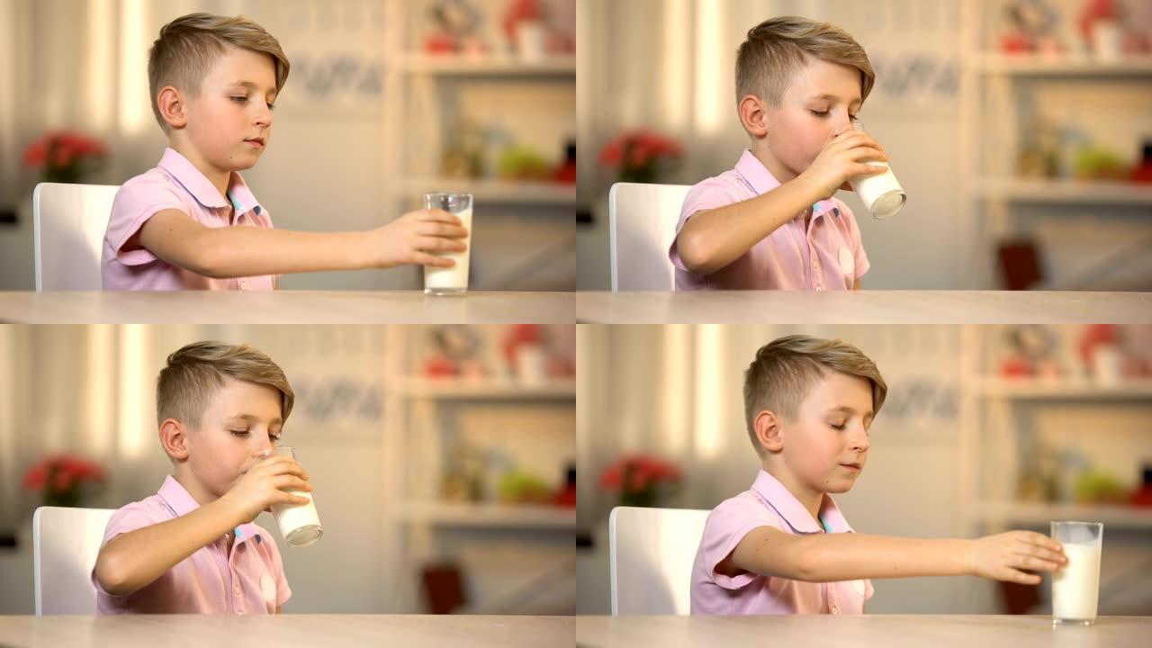 男孩从桌上的玻璃杯中喝新鲜的有机牛奶，早晨的能量食品，乳制品