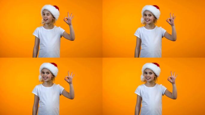 可爱的少女戴着圣诞老人帽子，显示ok标志和微笑，推荐