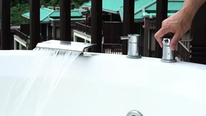 男人用手在热水浴缸上打开水