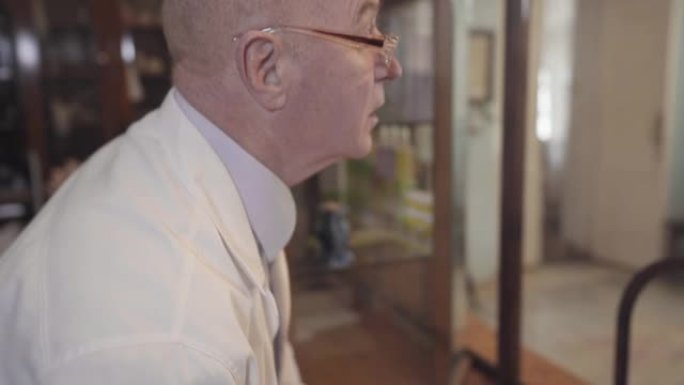 古代男性白人药剂师用羽毛笔书写和离开的肖像。成熟的秃头药剂师在他的工作地点。复古药店，复古药博物馆。