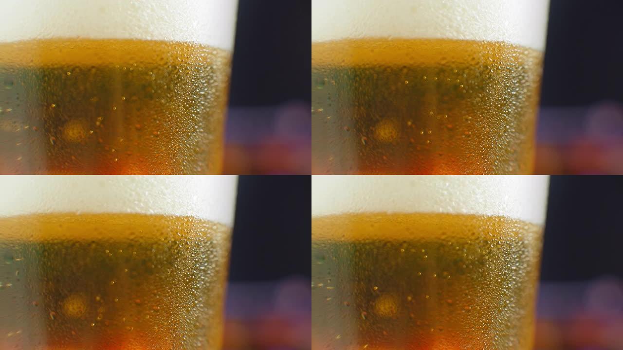 特写慢动作: 冰镇啤酒在玻璃杯中大滴和气泡在啤酒中。