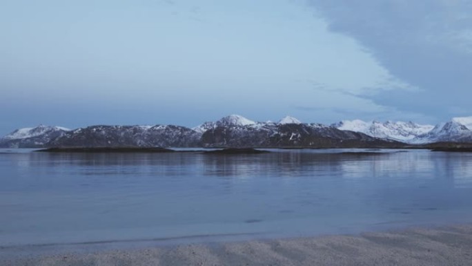 冬天特罗姆瑟海边的风景。积雪覆盖的山脉和杂草
