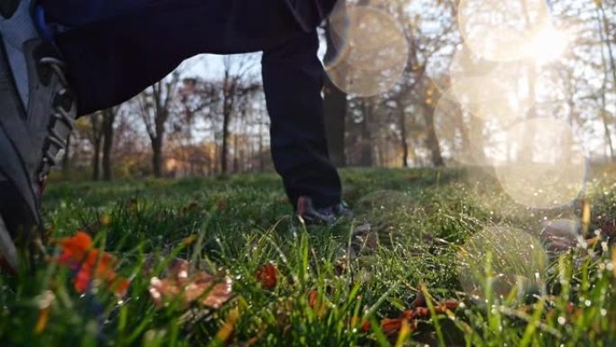 在树林里行走的鞋子的特写镜头。在公园里播撒秋叶。镜头光斑。以慢动作记录。