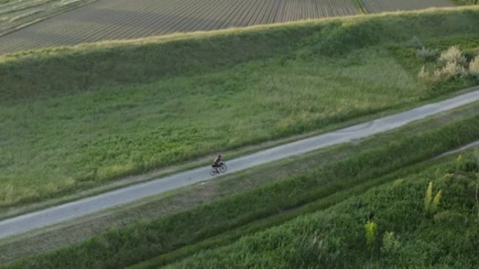 骑自行车的人在日落时沿着砾石路径骑自行车的空中无人机视图