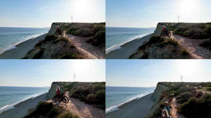 沿海岬角上骑自行车的夫妇的鸟瞰图