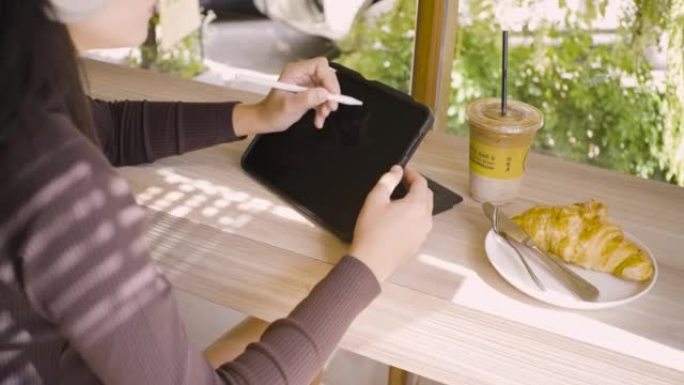 美丽的女孩工作免费局域网在咖啡馆工作，在桌子上工作，用数字平板电脑