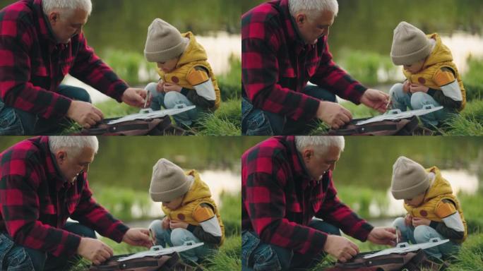 老渔夫正在向小孙子展示他的渔具，幸福的家庭在大自然中共同度过