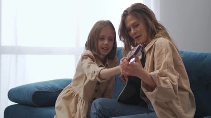 快乐的母女俩周末在家一起弹吉他，女人在教孩子弹吉他