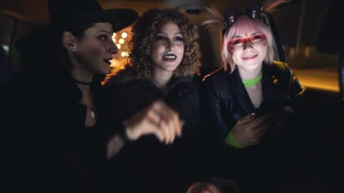 三名年轻女子乘坐出租车参加万圣节派对并使用手机
