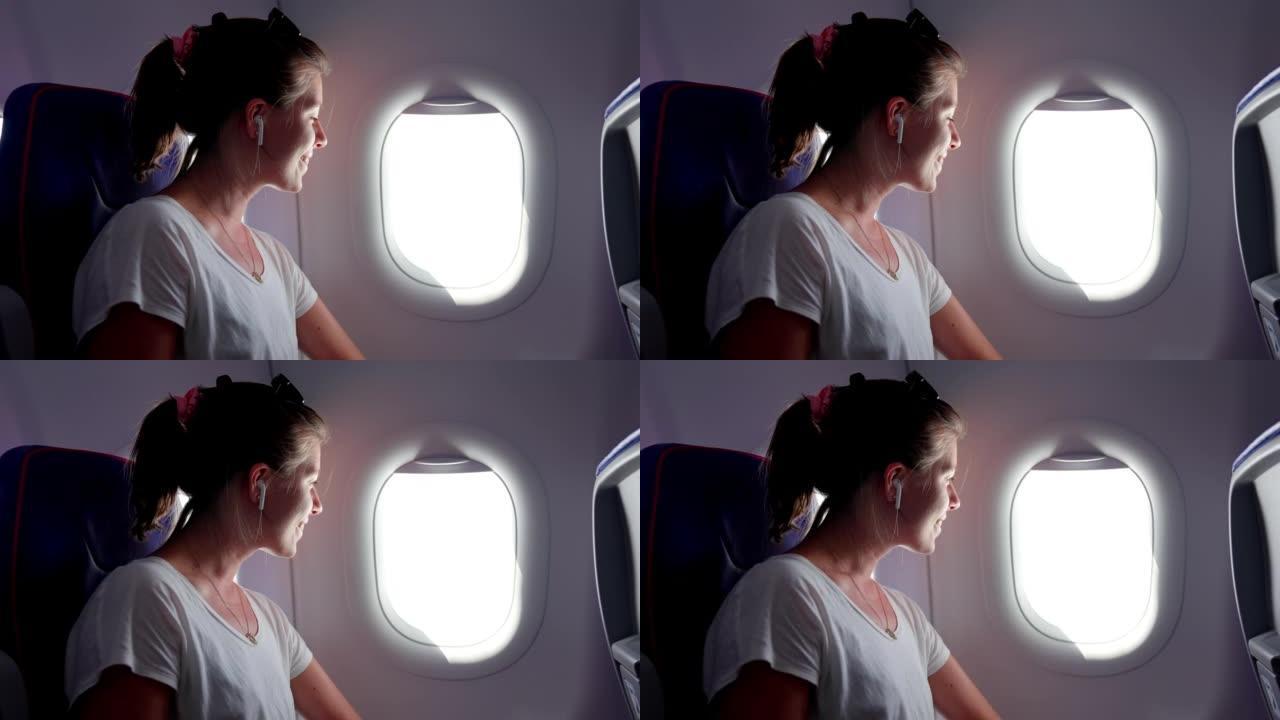 坐飞机旅行的年轻女子看着窗外。