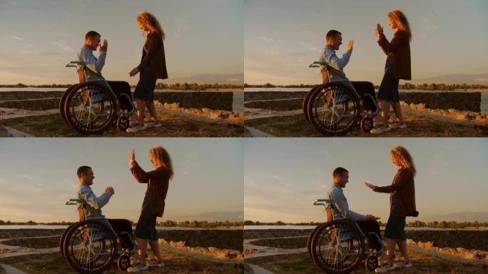 坐在轮椅上的年轻人在朋友的陪伴下玩草坪游戏。残疾人过着平凡的生活。女孩和残疾人在海滩上共度时光。