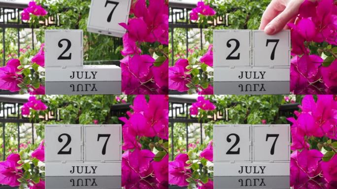 一个木制日历，有一个重要的活动，7月27日在一张有芙蓉花的桌子上，女人的手在日历上设定了日期。将日历