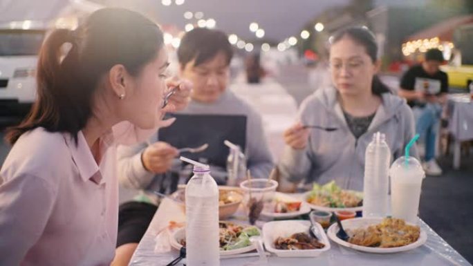 亚洲朋友晚上在the Foot Truck City聚会共进晚餐，分享食物并享受乐趣。