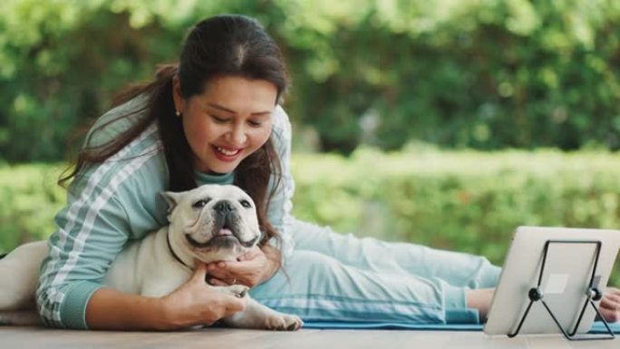 健康的女人早上和一只法国斗牛犬一起练习瑜伽。