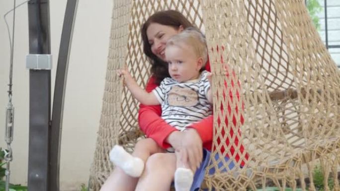 母亲带着快乐的小孩拥抱在吊椅上