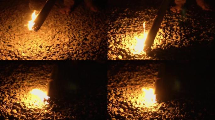 在漆黑的夜晚，竹棍制成的火把上的火焰照亮了