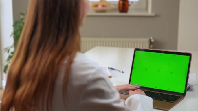 Chromakey笔记本电脑与模糊的医生在视频聊天中挥手问候患者。无法辨认的年轻白人妇女在医院在线咨