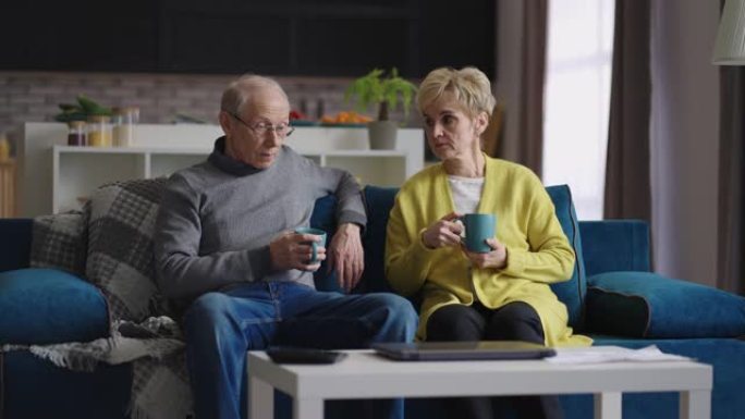 已婚的一对退休人员周末在家休息，老人和女人坐在公寓客厅的沙发上