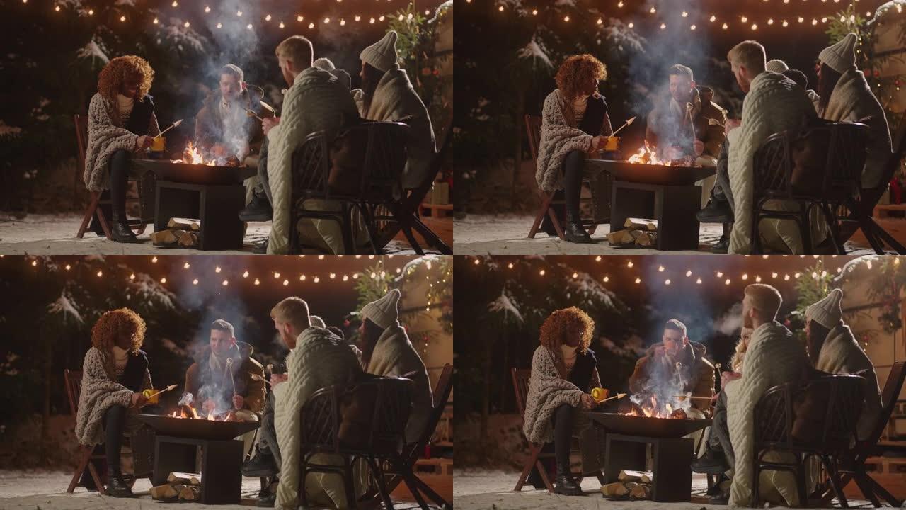 老好朋友在圣诞节之夜聚会，坐在篝火旁烤棉花糖