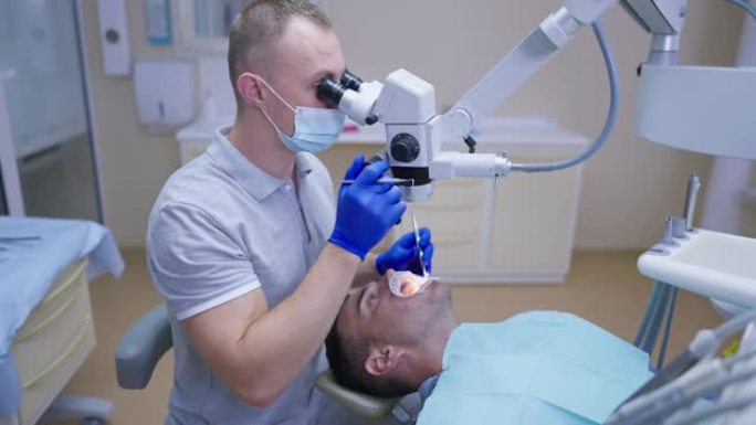 使用牙科牙髓双目显微镜检查患者口腔的侧面视图男性白人牙医在牙医椅上使用唇牵开器。集中专家医生在室内咨