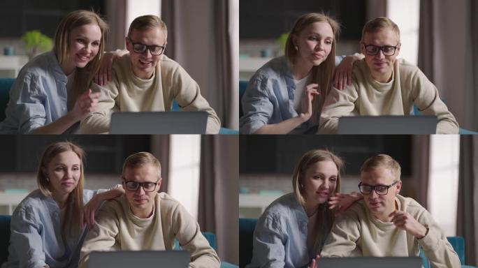 年轻可爱的已婚夫妇一起坐在新公寓沙发上的笔记本电脑上在互联网上聊天。搬迁概念
