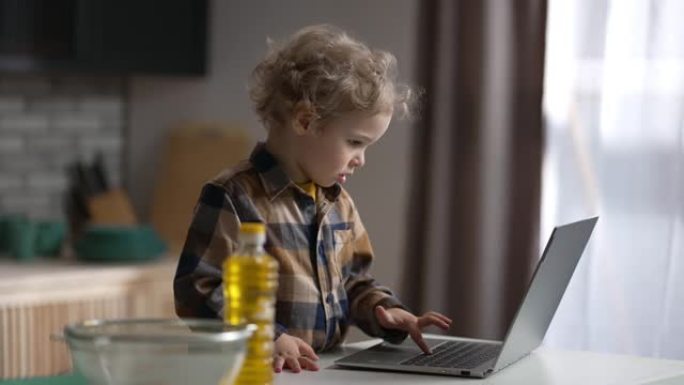 现代儿童正在使用带互联网的笔记本电脑，小男孩正在按下键盘上的按钮并在屏幕上查看