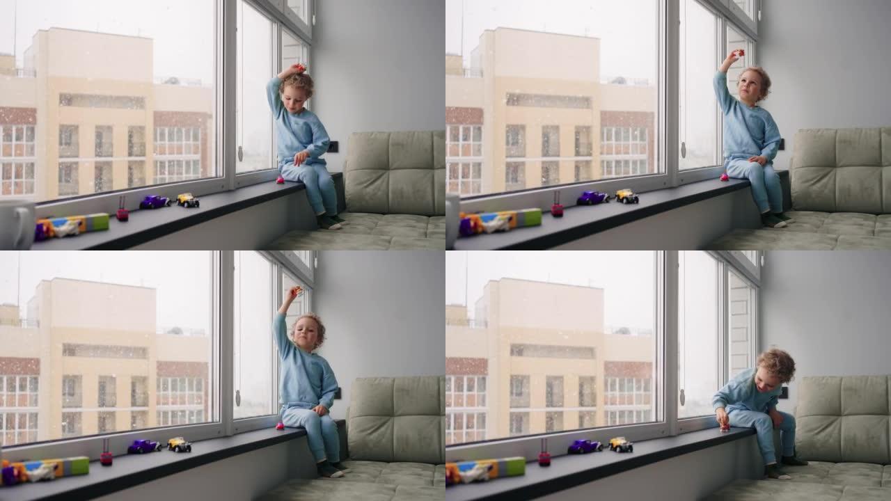 可爱的小男孩在冬天的现代公寓的儿童房里独自玩耍，雪落在indow后面