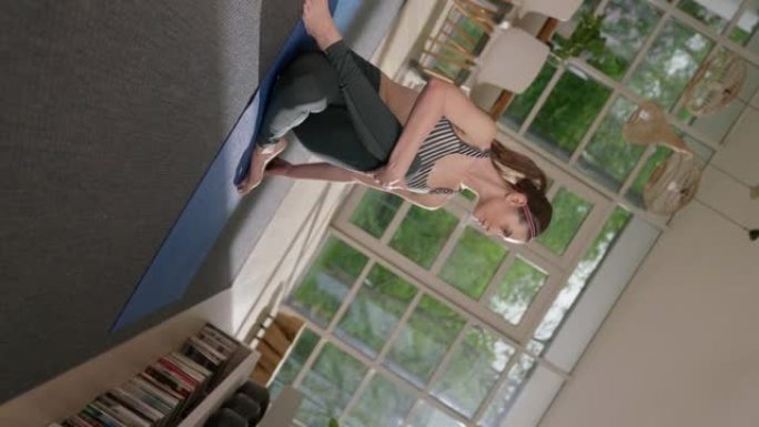 女运动员用笔记本电脑在瑜伽垫上做脊柱扭转。家庭锻炼。纺纱效果