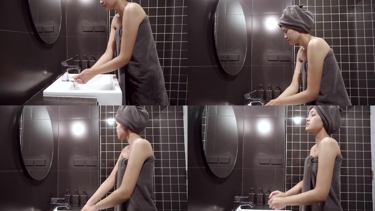 亚洲女性用干净的布擦干自己。洗澡后，清洗身体。在黑色浴室里。