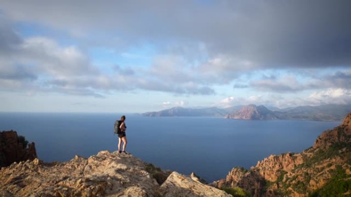 女徒步旅行者站在视线处，在日落时眺望海洋和悬崖海岸线