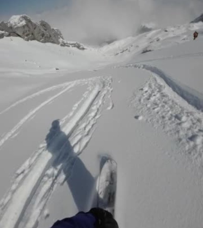 滑雪者下降新鲜的粉末雪山，可以欣赏下面阿尔卑斯山的景色