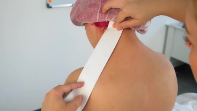 物理治疗师正在诊所将kinesio胶带应用于女性患者的背部。