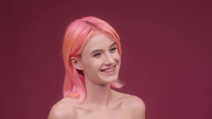 染成粉红色头发的年轻女子微笑着把手放在脸上