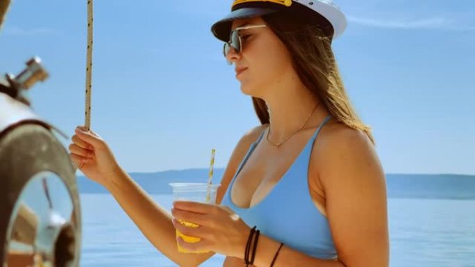 年轻女子在游艇上喝鸡尾酒时戴着船长的帽子